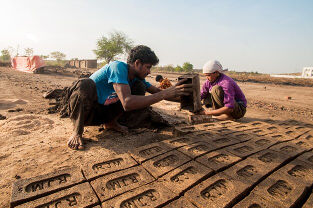 A construction site in Bangladesh with foreign workers collaborating with local workers, illustrating technology transfer and skill development in the infrastructure sector. The image shows modern construction equipment and safety measures being implemented.