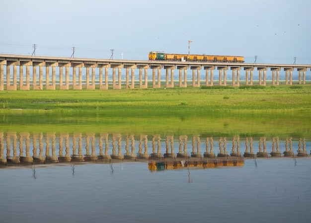 A long-distance train speeding across a bridge in rural Bangladesh, with lush green fields on either side, illustrating the connectivity and efficiency of railway transport.