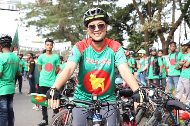 A close-up shot of a cyclist wearing the Bangladesh national jersey, focusing on their determined expression and the bicycle, symbolizing dedication and preparation for the National Cycling Competition 2025.