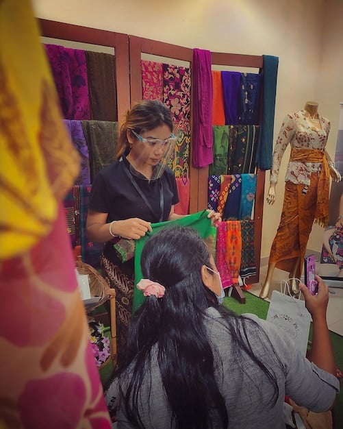 A Bangladeshi fashion designer is showcasing a collection of outfits featuring vibrant colors and unique patterns, blending traditional and modern styles.