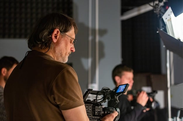 A close-up shot of a movie director intensely looking at a monitor on set, surrounded by equipment and crew members.