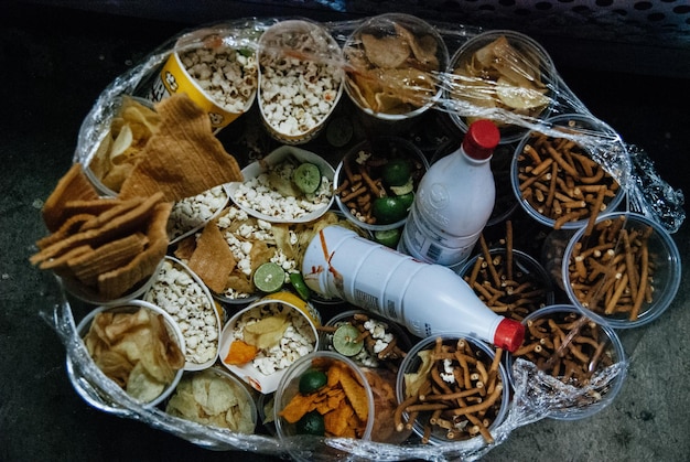 A close-up shot of various adulterated food items seized during a raid in Chittagong, Bangladesh. The items include falsely labeled spices, artificially colored sweets, and expired food products. The shot highlights the deceptive packaging and unhealthy ingredients used in these adulterated products.